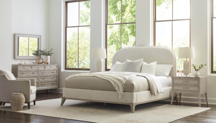 A bedroom with a bed, a stylish dresser, and a sleek mirror